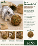 Rabbit rolling and chewing a large natural willow ball filled with hay and meadow flowers in an indoor play area.