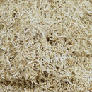 Close-up of chopped flax bedding showing short, pale fibrous pieces in varied shapes.