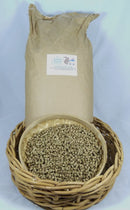 Paper sack behind a bowl of straw litter pellets displayed in a wicker basket.
